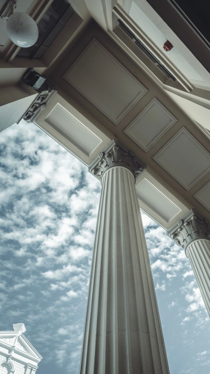 hero-img-01 Low-angle view of architectural columns against a cloudy sky in Fremantle, Australia.