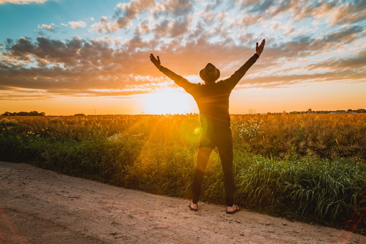 services-02 A man raises arms in freedom at sunrise in a rural field, expressing joy and connection with nature.